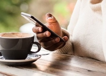 Woman drinking coffee and using her cellphone