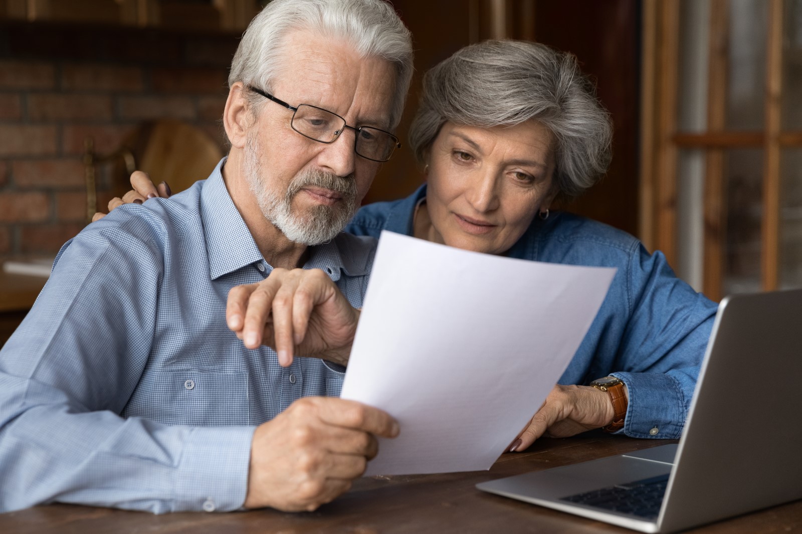 An older couple who is thinking about using home equity to purchase a new home reviews research at their laptop.