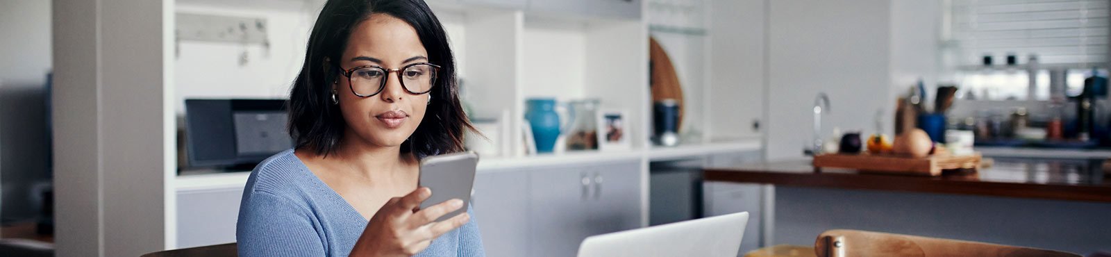 Woman at home using laptop and phone.