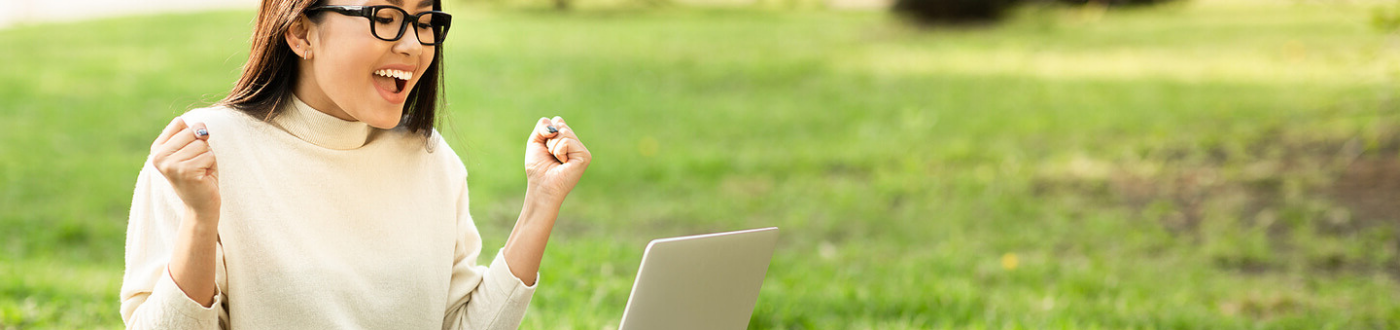 happy woman on laptop in park