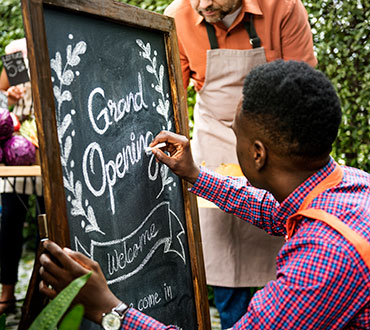 Man writing Grand Opening on chalkboard sign.