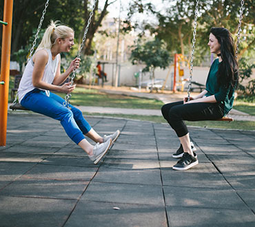 Two friends talking on swings.